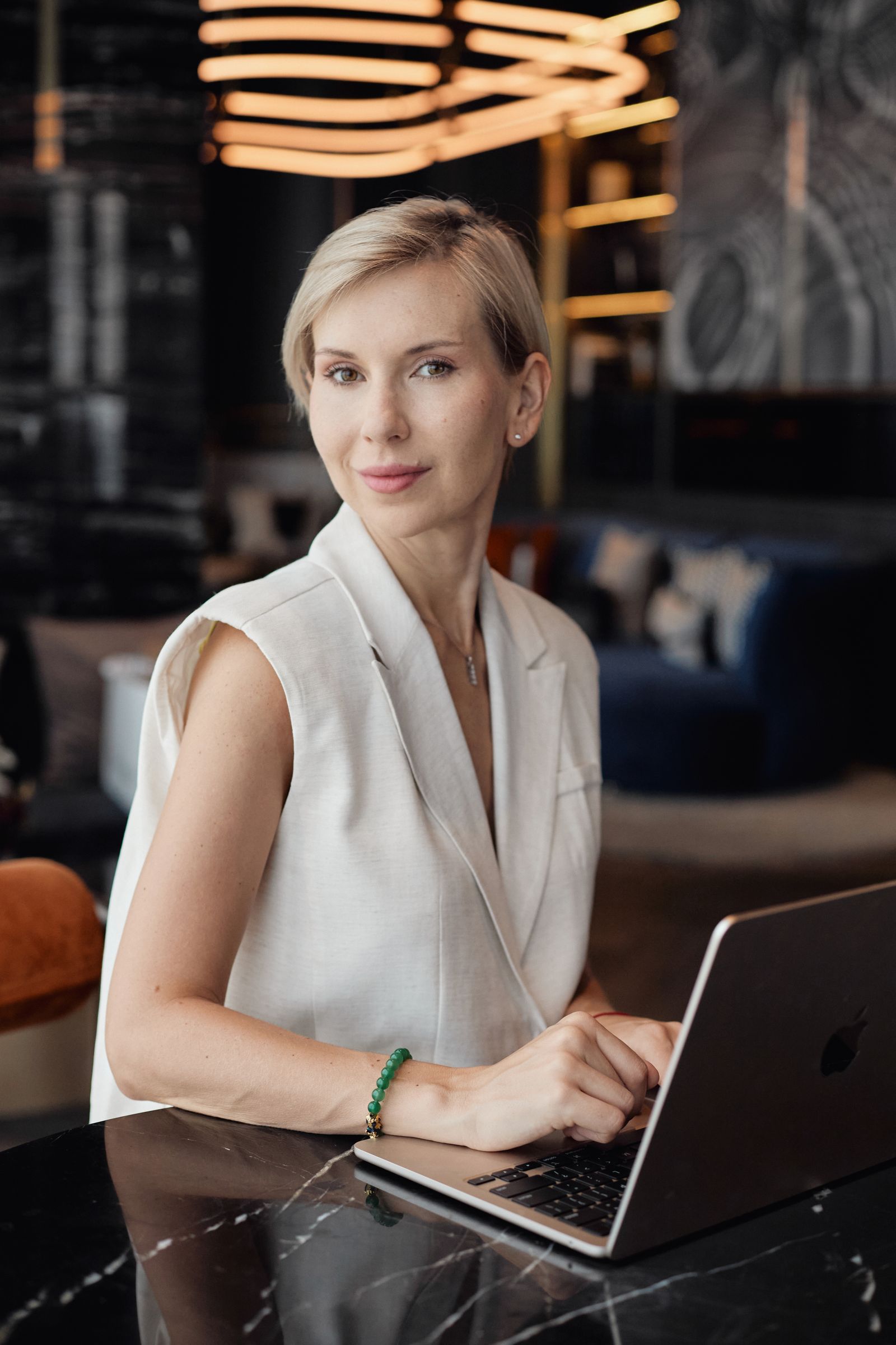 Katerina Andreeva standing against a city backdrop, holding a closed laptop